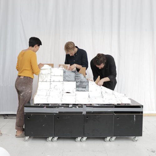 3 people assembling the printed segments of the model.
