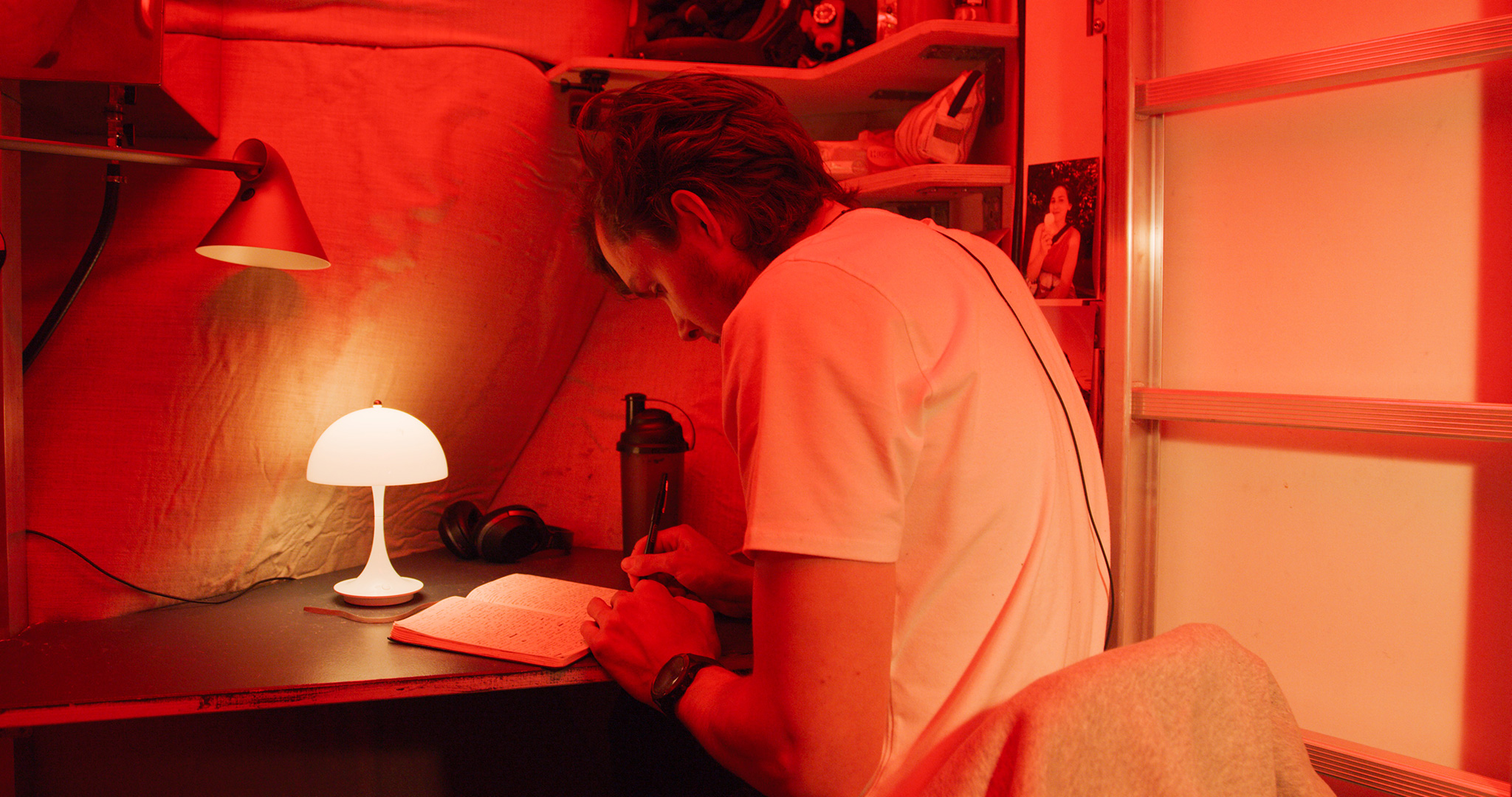 Karl-Johan sitting at his desk inside the Habitat writing in his notebook